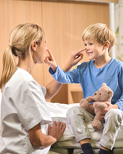 Nurse and little male patient playfully tap each other on the tip of the nose