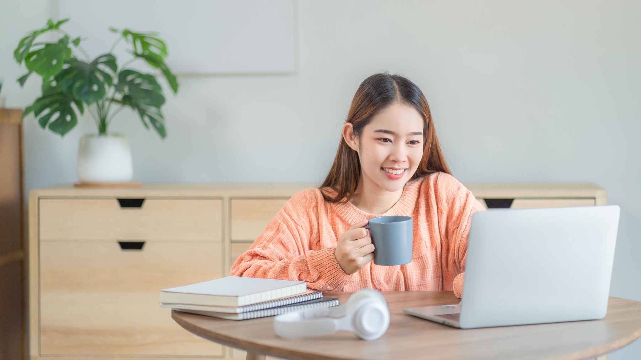 Young woman working on her notebook computer at her home. Work from home concept.
