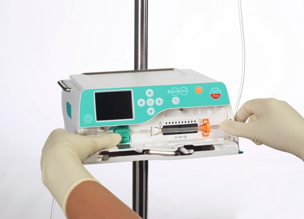 Oncology patient with glasses sitting on the chair and nurse with gloves handling cytoset 