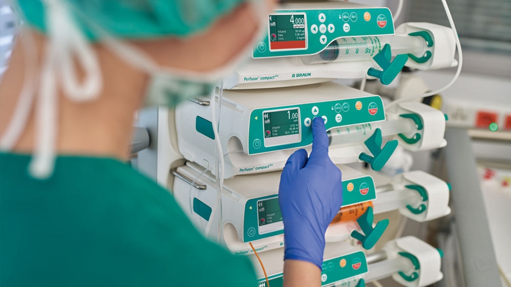 A female healthcare professional is adjusting the infusion pumps