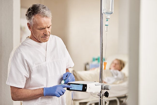 nurse taps her finger on the display of an infusion pump