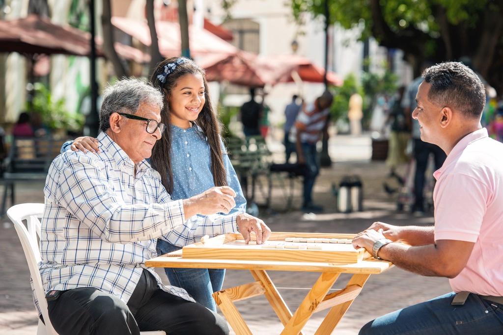 A person wearing glasses stands confidently and with crossed arms in a vast field.
